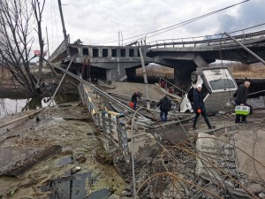 FOTO que refleja la guerra: Residentes cruzan con su equipaje un puente destruido en Ucrania