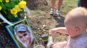 La imagen desgarradora de la guerra: una niña ucraniana celebra su primer cumpleaños ante la tumba de su padre